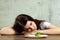 Sad young brunette woman dealing with anorexia nervosa or bulimia having small green vegetable on plate. Dieting problems, eating