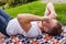 Sad young man lying in the summer park with Hidden Face. He is c