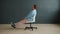 Sad young man spinning in office chair indoors in studio on dark background