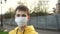 Sad young man teenager puts on a protective medical blue mask on the background of a metal fence