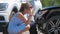 Sad young woman driver standing near her smashed car looking shocked on crashed vehicles in road accident