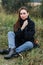 Sad young woman sitting alone on grass outdoors. Hope. Sadness. Loneliness. Autumn weather