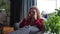 A sad young woman is suffering from a severe headache. Curly woman sits on the couch and grimaces from pain in the