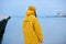 Sadness woman standing alone on beach and look at distant city. loneliness woman in yellow rain coat walking coast