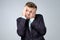 Sads young business man in suit, white shirt putting hand on head on grey wall background in studio