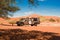 Safari jeep between orange dunes in Namibia. Landscape in Namib Desert, Namibia