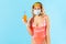 Safe drink with straw! Positive woman in swimsuit, hygienic face mask and gloves, holding cocktail with disposable straw