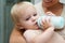 Safe in his mothers arms. A baby boy drinking milk from his bottle while being held by his mother.