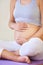 Safe pregnancy exercise. A cropped image of a regnant woman holding her belly while sitting with her legs crossed.