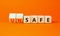 Safe or unsafe symbol. Concept word Safe Unsafe on wooden cubes. Beautiful orange table orange background. Business safe or unsafe