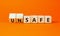 Safe or unsafe symbol. Concept word Safe Unsafe on wooden cubes. Beautiful orange table orange background. Business safe or unsafe