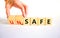 Safe or unsafe symbol. Concept word Safe Unsafe on wooden cubes. Businessman hand. Beautiful white table white background.