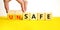 Safe or unsafe symbol. Concept word Safe Unsafe on wooden cubes. Businessman hand. Beautiful yellow table white background.