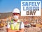 Safely Labor Day. Builder in medical mask and hardhat stands cross handed opposite construction site