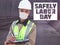 Safely Labor Day. Construction worker dressed in medical mask, uniform and white hardhat stands with clipboard at metro tunnel