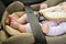 Safety concept, protection of child in travel, children feet in baby seat. Small baby sitting in special car seat with safety