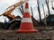 Safety cone, close-up, against background of a bucket truck and pollarding trees in the Ukrainian countryside. Old shabby road