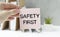 Safety first in unsafe workplace concept photo. Hand of staff is holding the text sign with blurred background