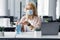 Safety and health protection at work in office. Millennial woman in protective mask with smart watch uses antiseptic at
