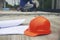 Safety helmet hard hat, blueprint, and drawings paper for engineer, safety officer or architect, place on wooden floor. Orange