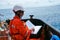 Safety officer, standing on an industrial ship, wearing overalls, a helmet, safety goggles and holding a clipboard with checklists