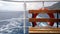 Safety on a passenger vessel: a bench and a lifeline. Visible trace of the sailing ship and mountains in the distance