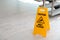 Safety sign with phrase Caution wet floor near stairs