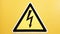 Safety sign yellow and black glued on a yellow wall. High voltage lightning in a triangle caution caution danger electricity death