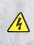 a safety sign yellow and black on silver metal background electric bolt in triangle safety caution careful