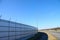 Safety wall with barbed wire and spikes on top of a fence provide security - blue sky background