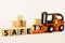 Safety at work concept with orange forklift with wooden blocks on white background