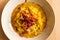 Saffron risotto close up, classic yellow colorful italian food staple dish on white plate on wooden table with speck, a gourmet