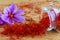 Saffron stigmas scattered on a wooden surface from a glass bottle. Saffron crocus flowers