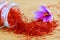Saffron stigmas scattered on a wooden surface from a glass bottle. Saffron crocus flowers.