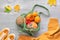 Safran yellow and orange pumpkins in mesh bag with yellow sweater sleave. Creative Autumntime background. Autumn flat lay on light