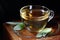 Sage herbal leaf tea or infusion in a glass cup with herb leaves nearby on wooden background