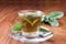 Sage tea in transparent teacup, with fresh leaf around,