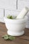 Sage in a white granite pestle and mortar. With grey brick background