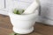 Sage in a white granite pestle and mortar. With grey brick background