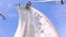 Sail boat navigating in the ocean sunny day showing the wooden parts and Closeup of the sail of a wooden antique