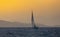 Sail boat in open sea at golden hour in evening. Mountains Silhouette in background