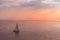 Sail boat on pink ocean under pink early morning sunlight off Lahaina, Maui, Hawaii, USA