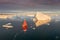 Sail boat with red sails cruising among ice bergs during sunset. Disko Bay, Greenland. Climate change and global warming