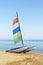 Sailboat catamaran with multi-colored flag on a background of blue sea