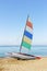 Sailboat catamaran with multi-colored flag on a background of blue sea