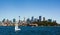 Sailboat crossing the deep blue waters of Sydney Harbor against a backdrop of the city skyline