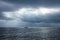 Sailboat in the dark sea, only a few rays of light illuminate the sea