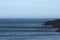 A sailboat in the distance in the sea in the evening sunlight near the stone Cape sails to the dream