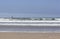 A Sailboat On the Horizon as a Foamy Ocean Wave Breaks