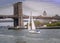 Sailboat on the hudson river closing on manhattan bridge New York